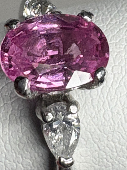 Platinum ring with an oval pink sapphire and two pear-shaped diamonds.