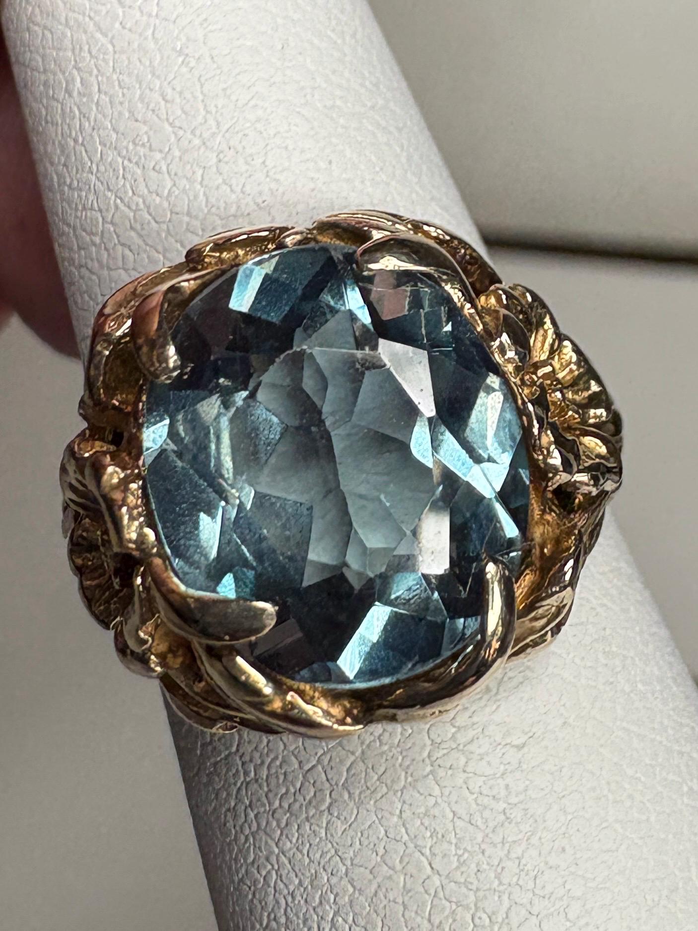 Large oval blue synthetic spinel ring with floral accents in 10k gold.