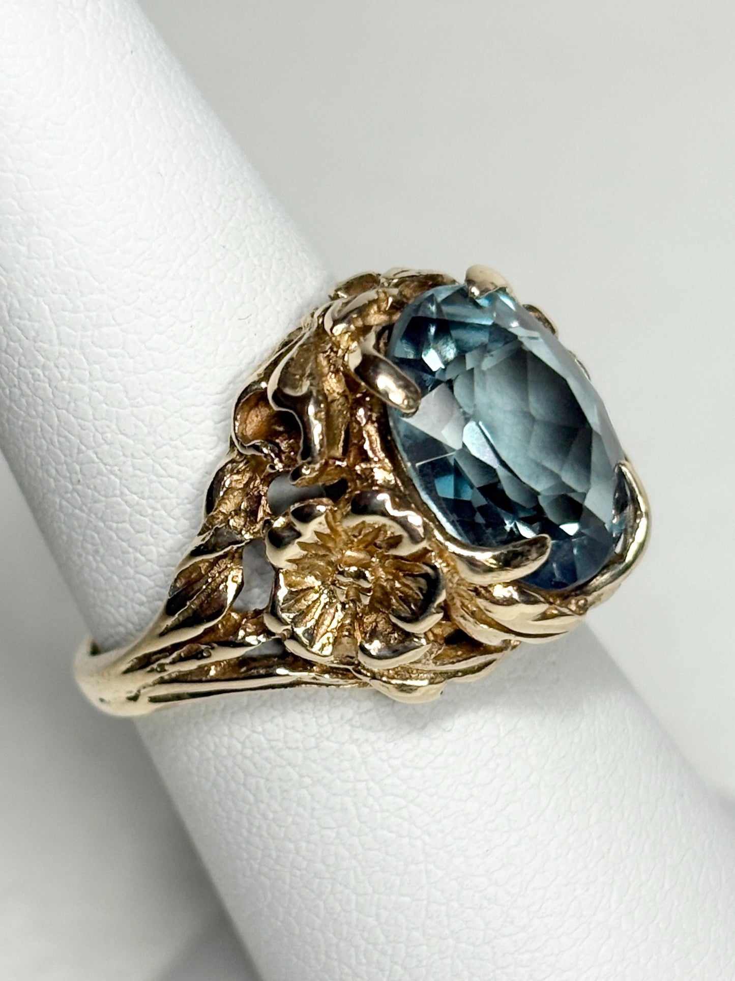 Large mid-century 10k gold ring with a blueish synthetic spinel and floral details.