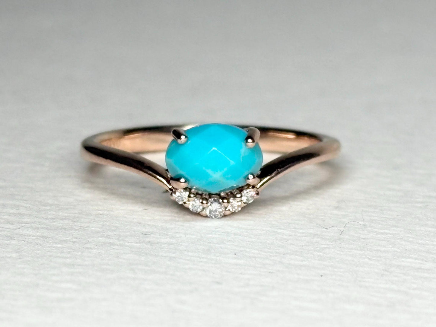 A rose gold ring with a checkerboard faceted turquoise and diamond accents.