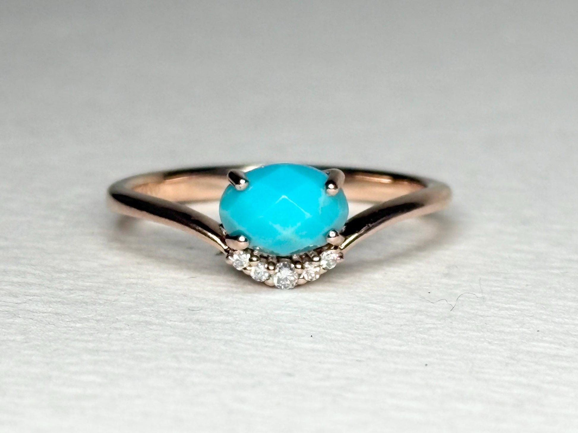 A rose gold ring with a checkerboard faceted turquoise and diamond accents.