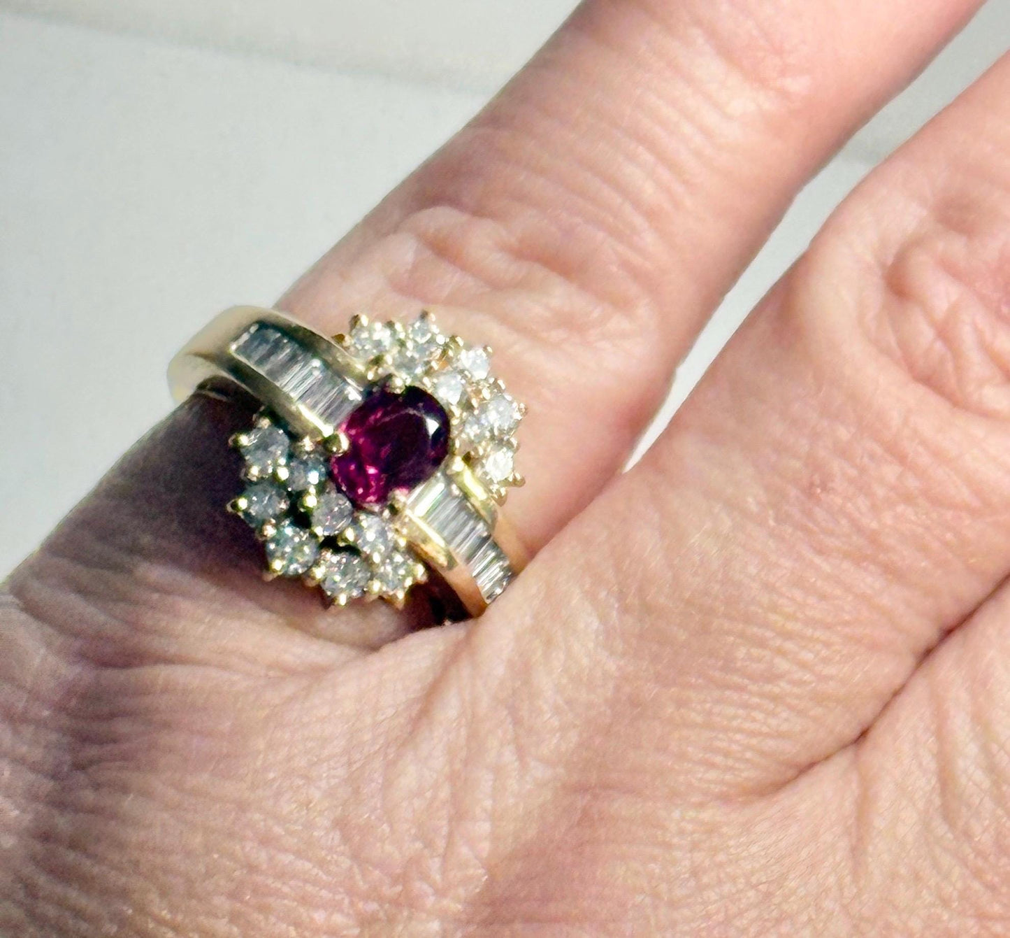 A vintage 18k gold cocktail ring with a ruby center surrounded by diamonds and baguette diamonds.