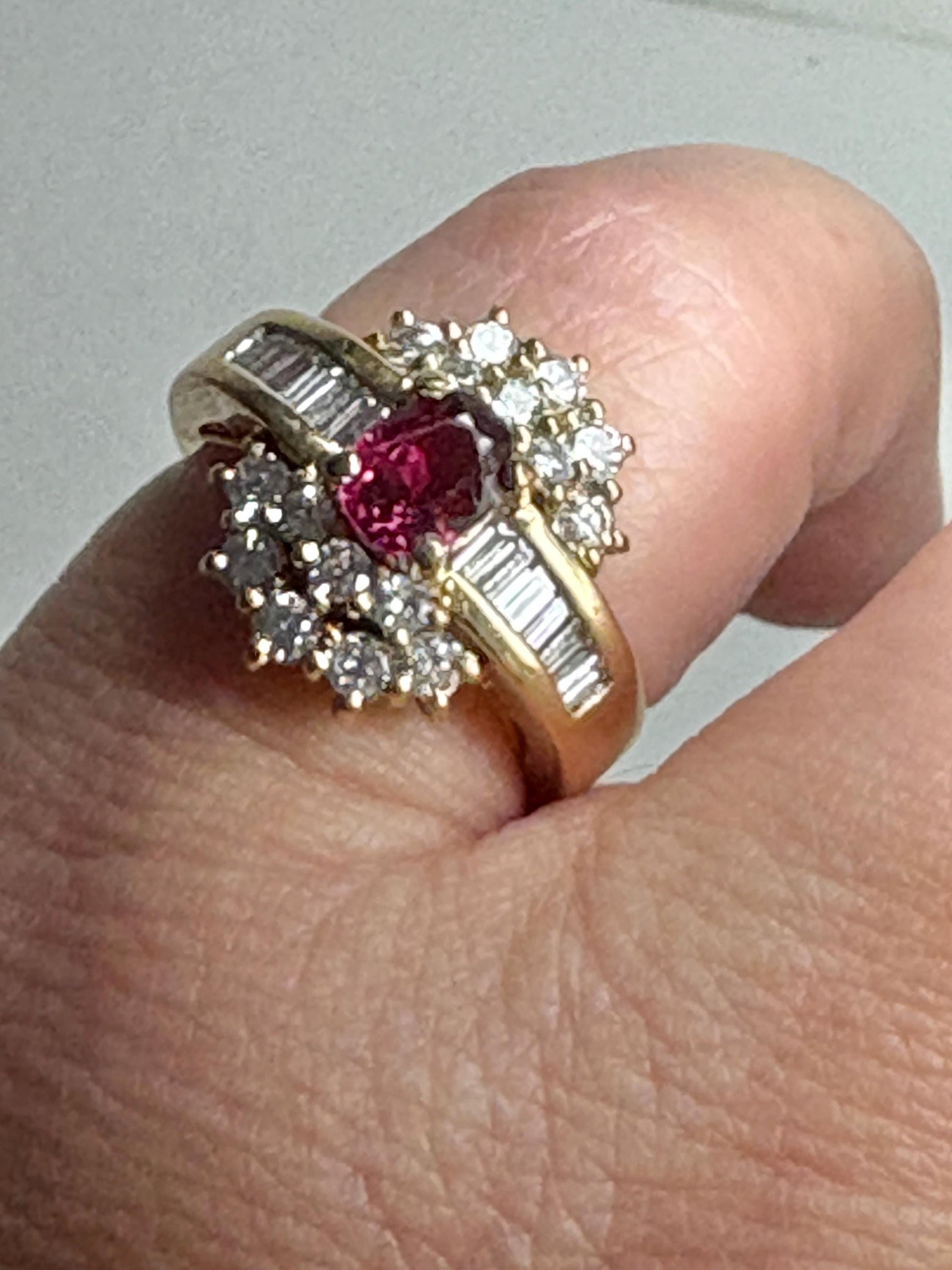 18k gold ring with a ruby center surrounded by baguette and round diamonds.