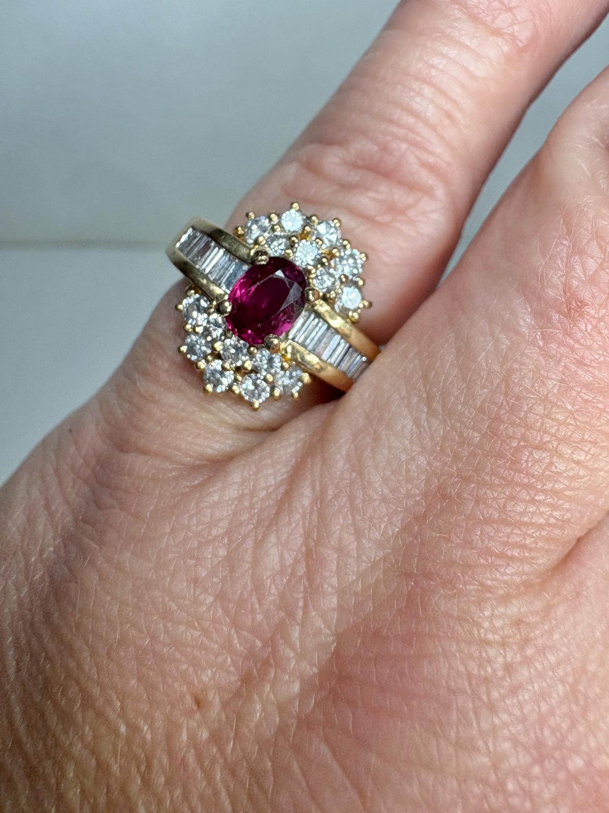 A vintage 18k gold cocktail ring with a ruby center surrounded by diamonds and baguette diamonds.