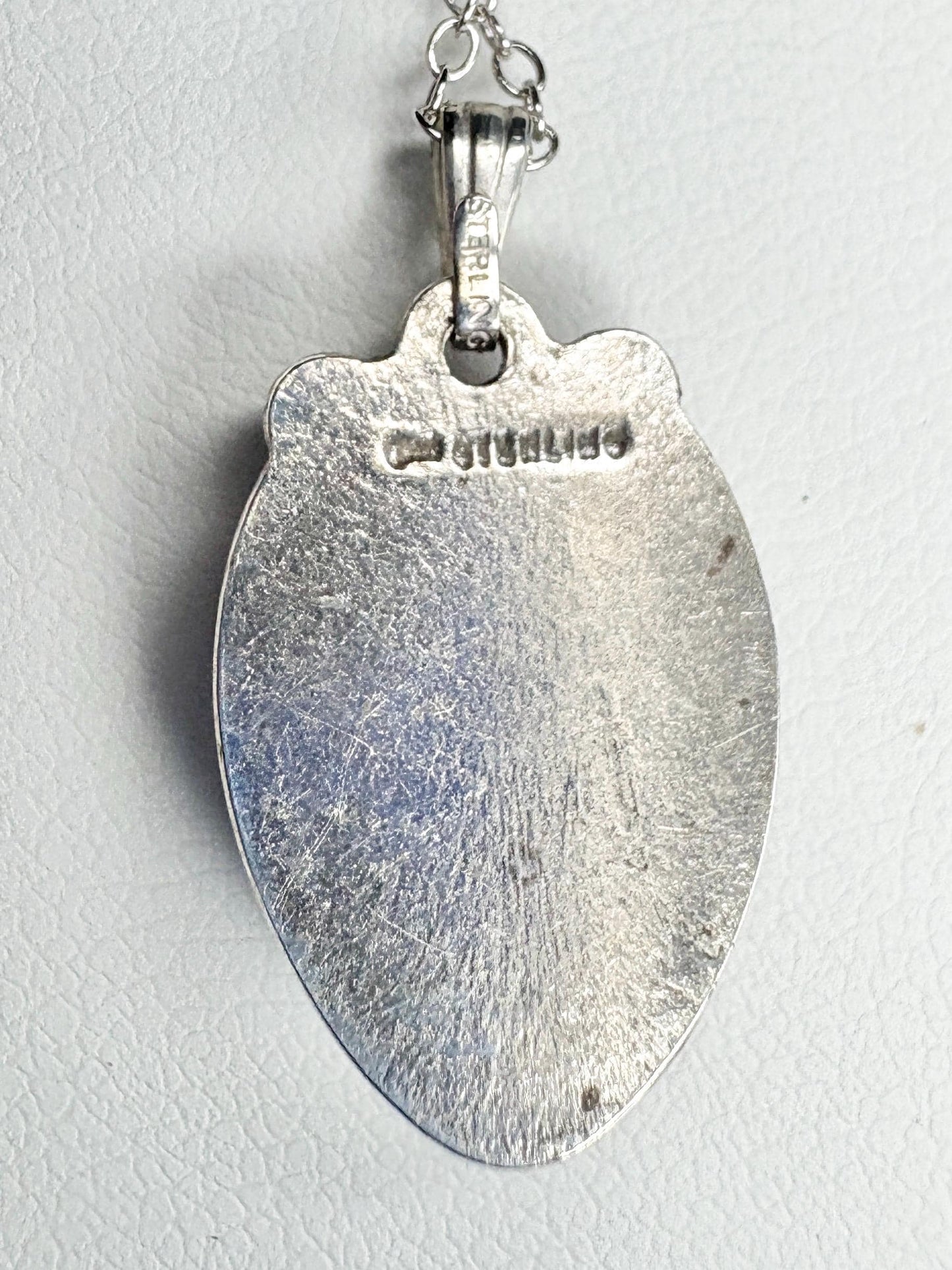 Sterling silver pendant necklace with a textured surface and a visible "STERLING" stamp.