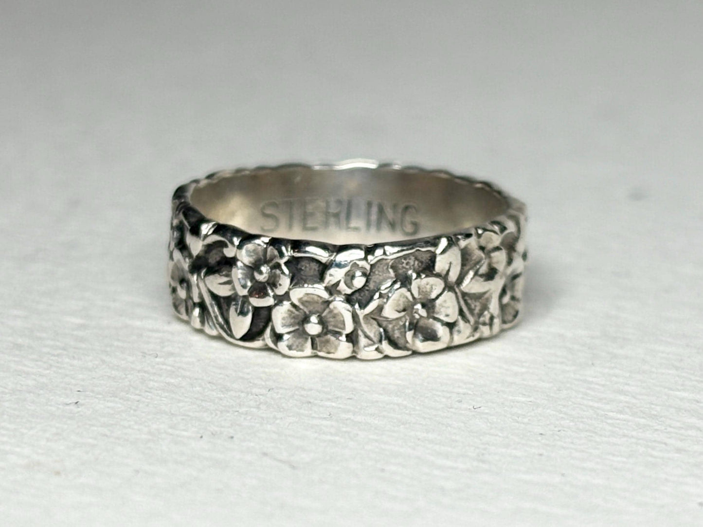Sterling silver eternity band ring with forget-me-not floral engraving.