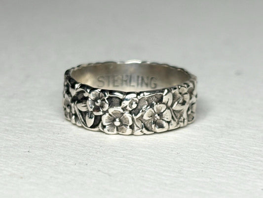 Sterling silver eternity band ring with forget-me-not floral engraving.
