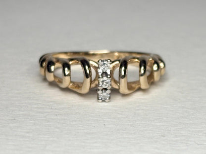 Vintage 14k gold band ring with ribbon loops and three small diamonds.