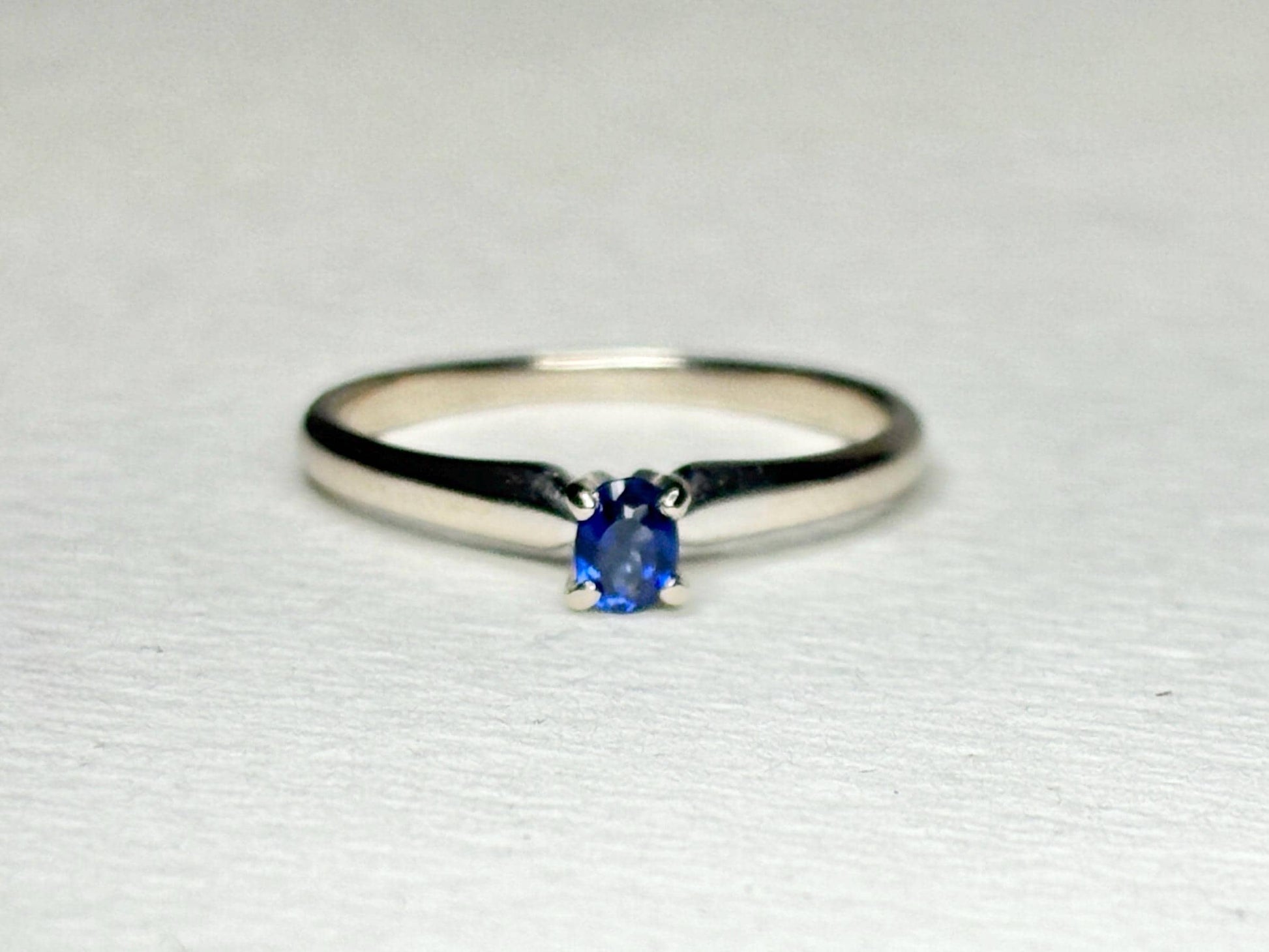 A vivid violetish blue oval sapphire solitaire in a 14k white gold ring.