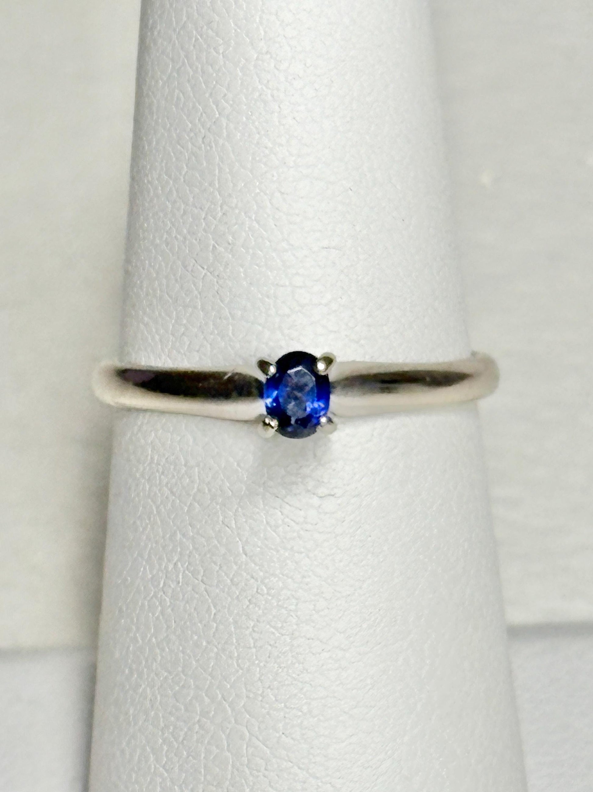 A vivid violetish blue oval sapphire solitaire in a 14k white gold ring.
