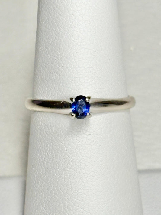 A vivid violetish blue oval sapphire solitaire in a 14k white gold ring.