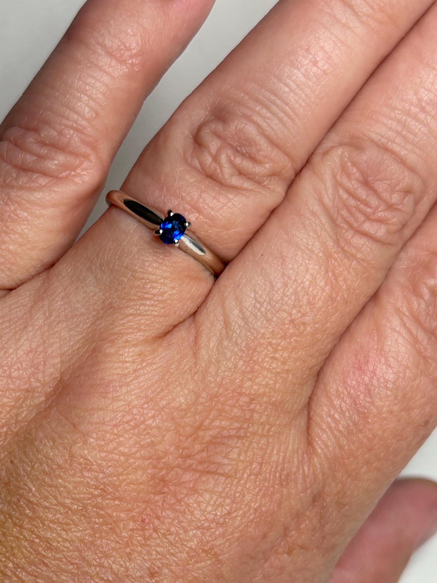 A vivid violetish blue oval sapphire solitaire in a 14k white gold ring.