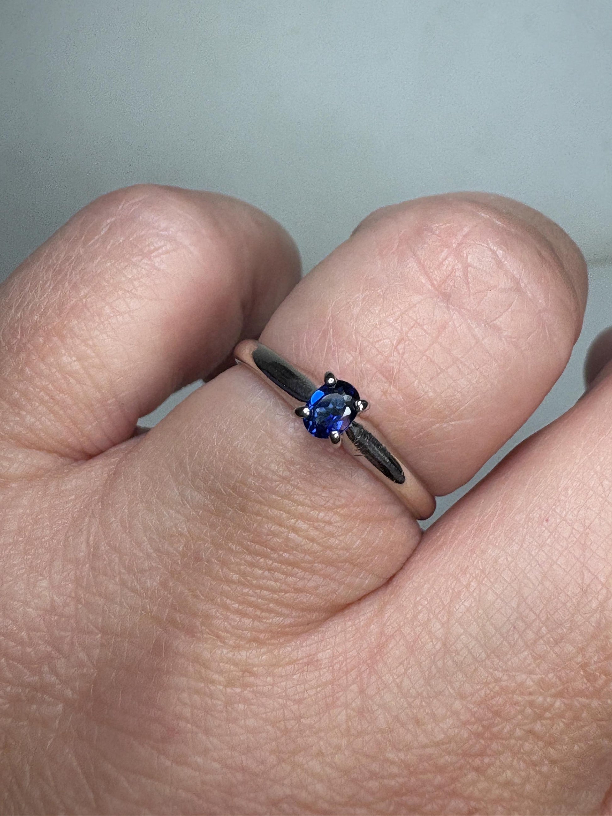A vivid violetish blue oval sapphire solitaire in a solid 14k white gold ring.