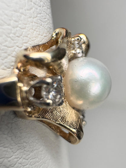 A 14k gold ring with a pearl and diamonds in a bow design.