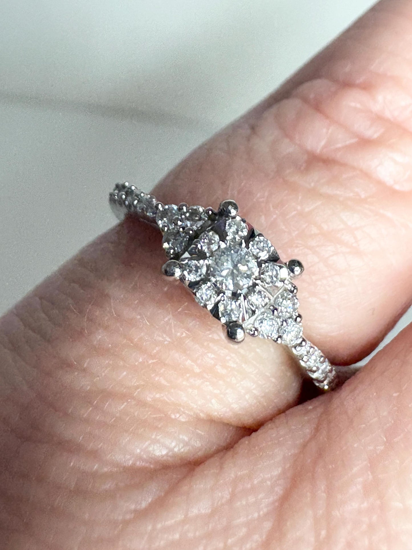 A white gold ring with a squared diamond halo cluster and diamond-accented band.