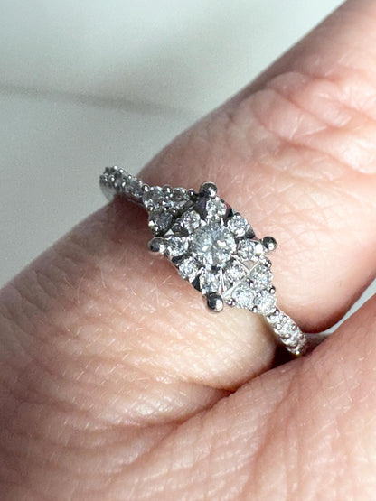 A white gold ring with a squared diamond halo cluster and diamond-accented band.