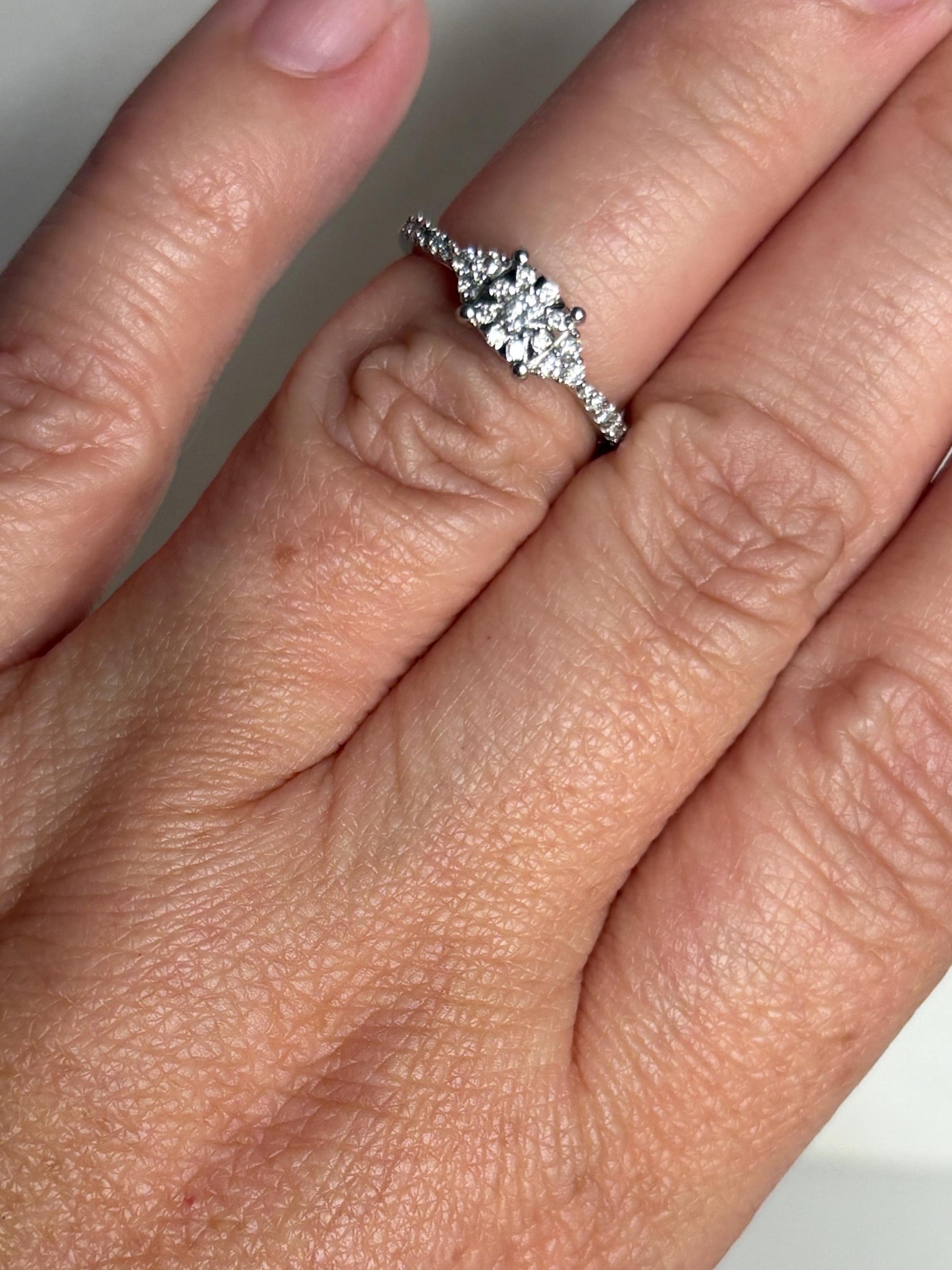 A white gold ring with a squared diamond cluster on a size 4.75 finger.