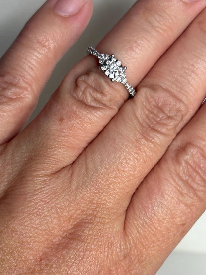 A white gold ring with a squared diamond cluster on a size 4.75 finger.