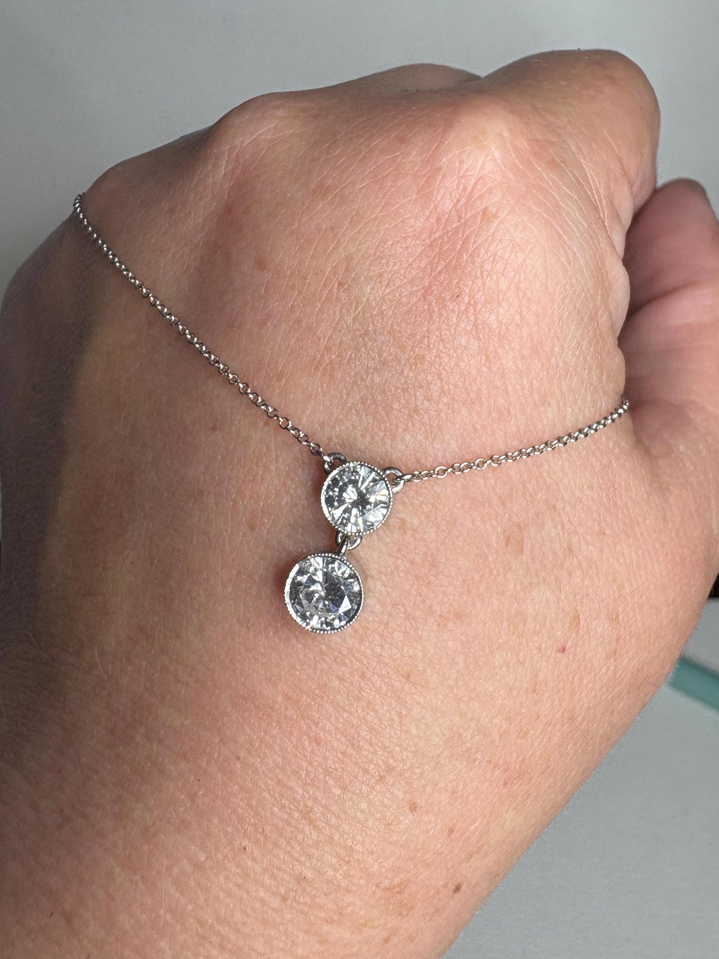 A 14k white gold necklace with two solitaire diamonds on an adjustable chain.