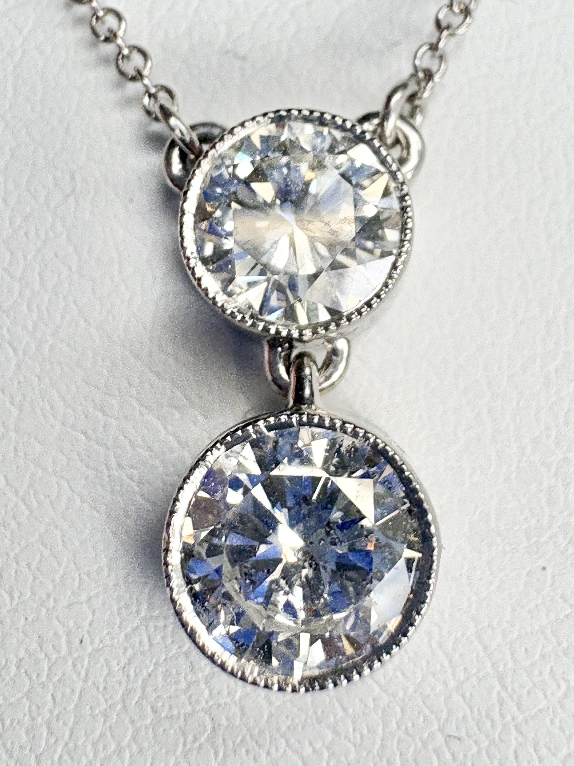 A 14k white gold necklace with two bezel-set natural diamonds.