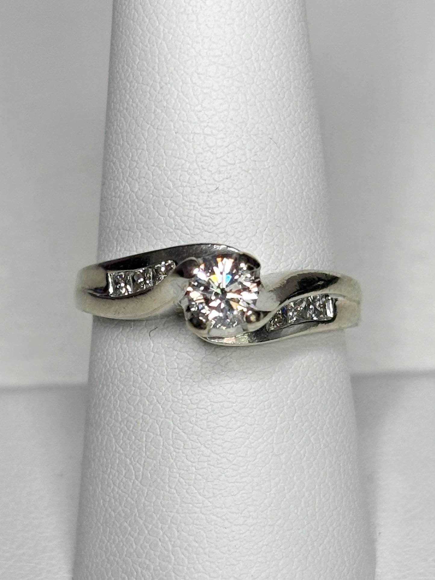 A vintage 14k white gold engagement ring with a central diamond and channel-set side diamonds.