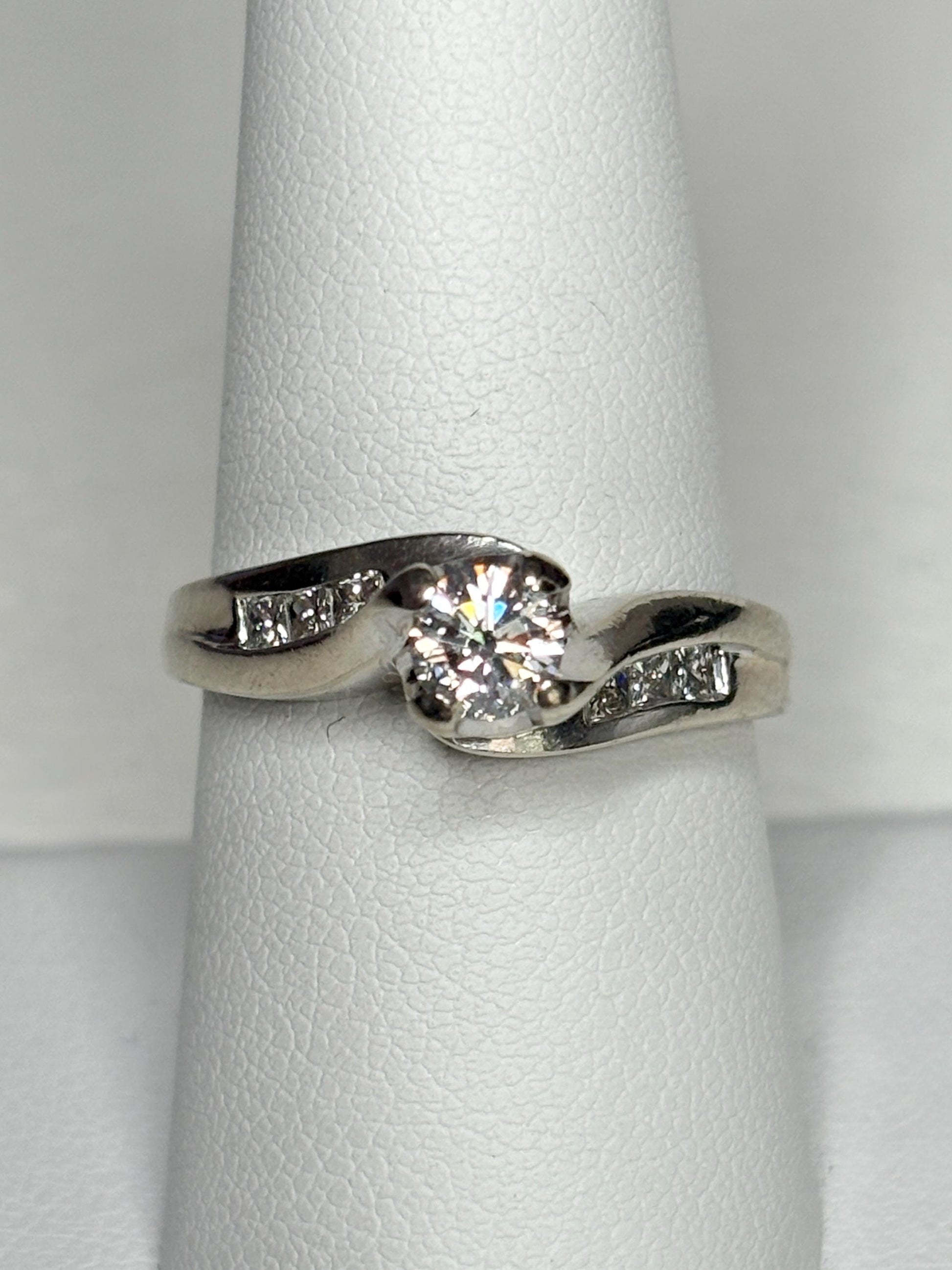 A vintage 14k white gold engagement ring with a central diamond and channel-set side diamonds.