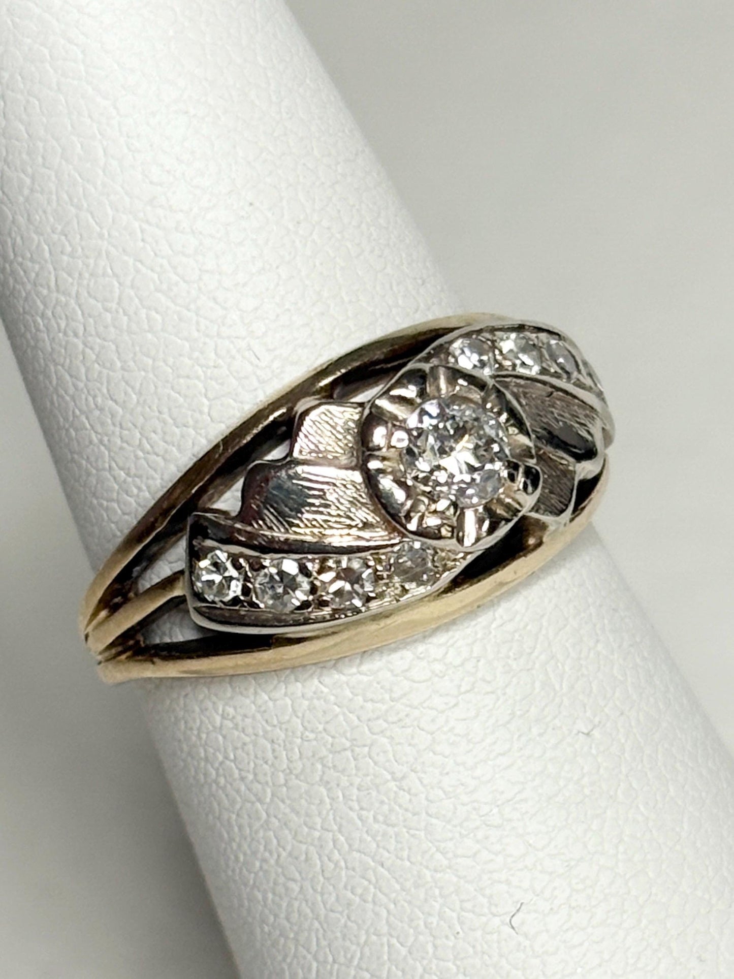 Mid-century two-tone 14k gold ring with a central diamond and smaller accent diamonds.