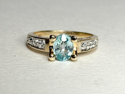 Oval blue zircon and clear side stone two-tone 14k gold ring.