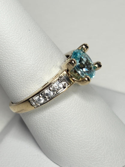 14k gold ring with oval blue zircon and clear side stones.