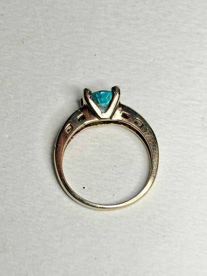 14k gold ring with a blue oval zircon and clear side stones.
