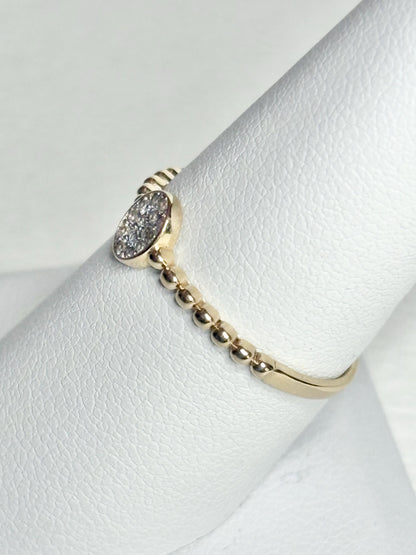 Dainty 14k yellow gold ring with a beaded band and an oval pave-set crystal cluster.