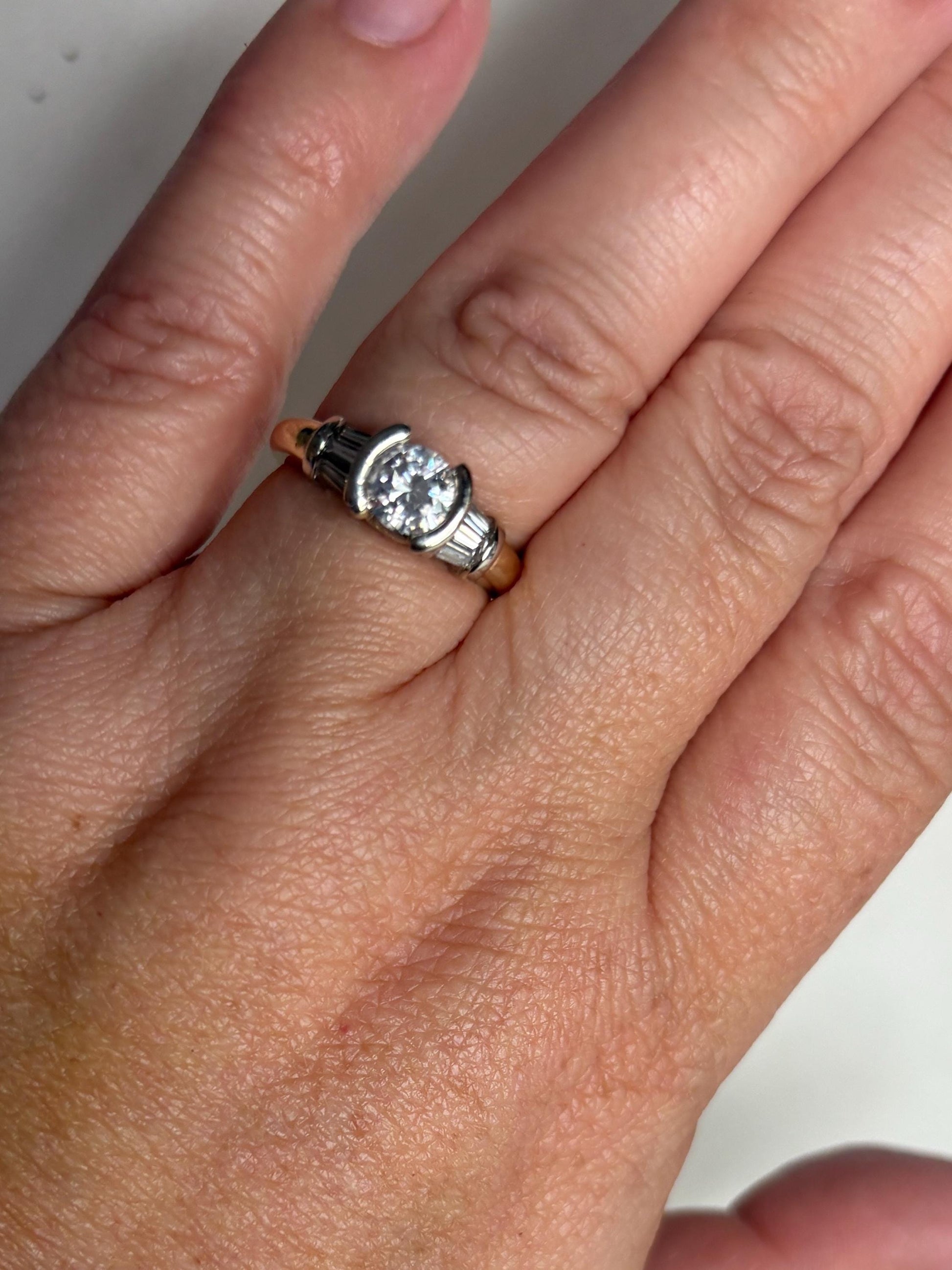 Two-tone 14k gold ring with a round diamond and baguette side stones.
