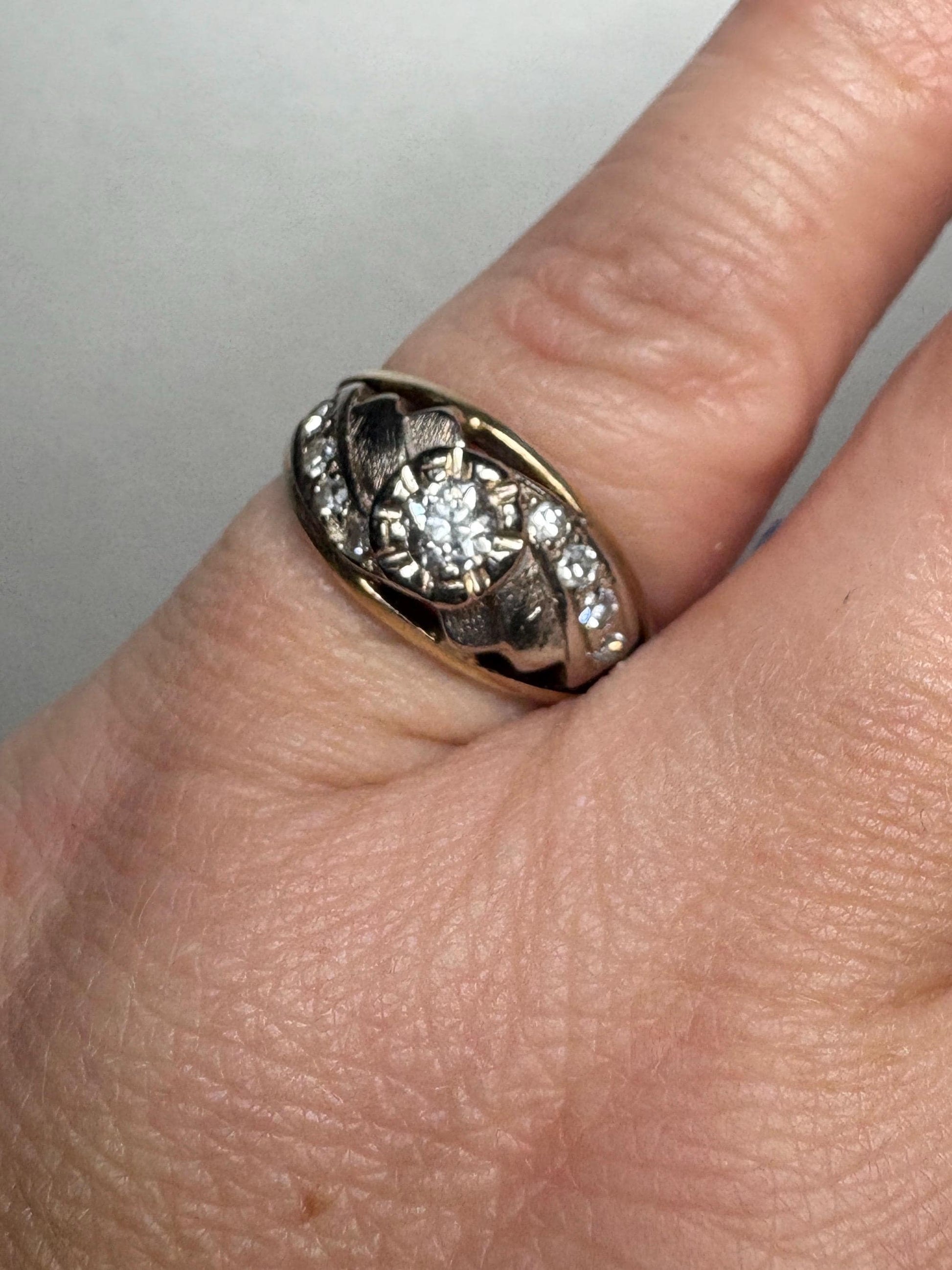 Mid-century two-tone 14k gold ring with a central diamond and smaller side diamonds.