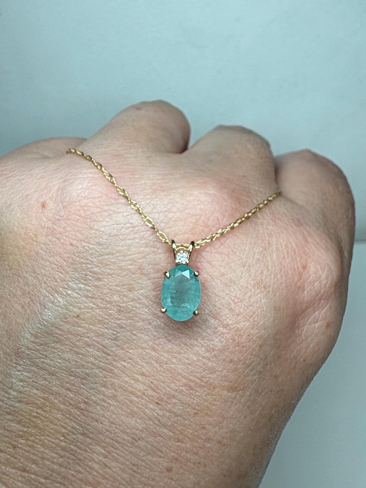 14k gold necklace with an oval grandidierite and diamond pendant.