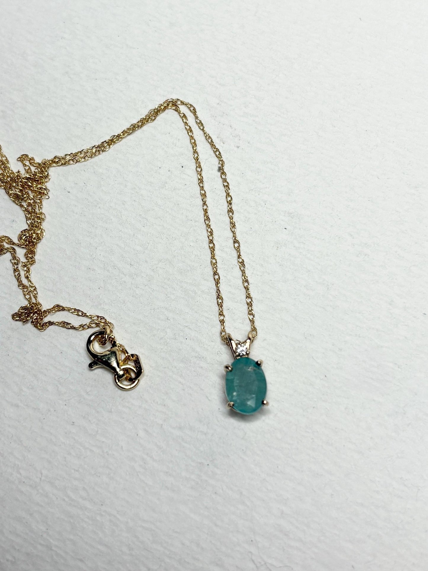 14k gold necklace with an oval grandidierite and diamond pendant.