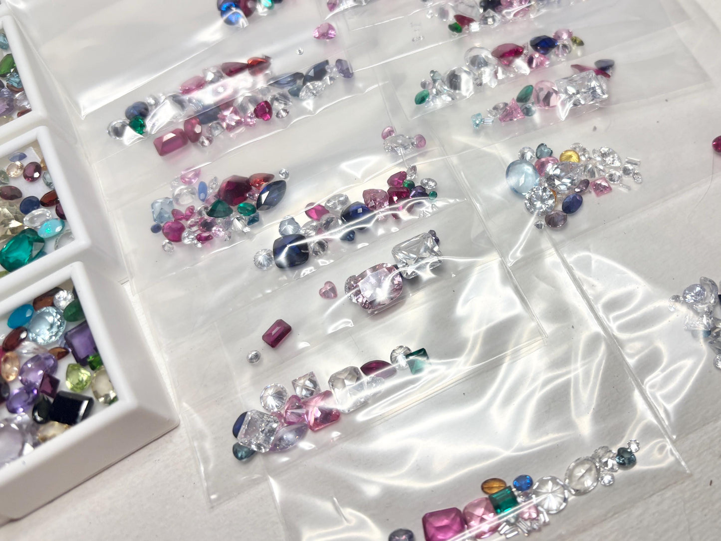 Assortment of faceted and cabochon gemstones in plastic bags.
