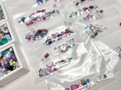 Assortment of faceted and cabochon gemstones in plastic bags.