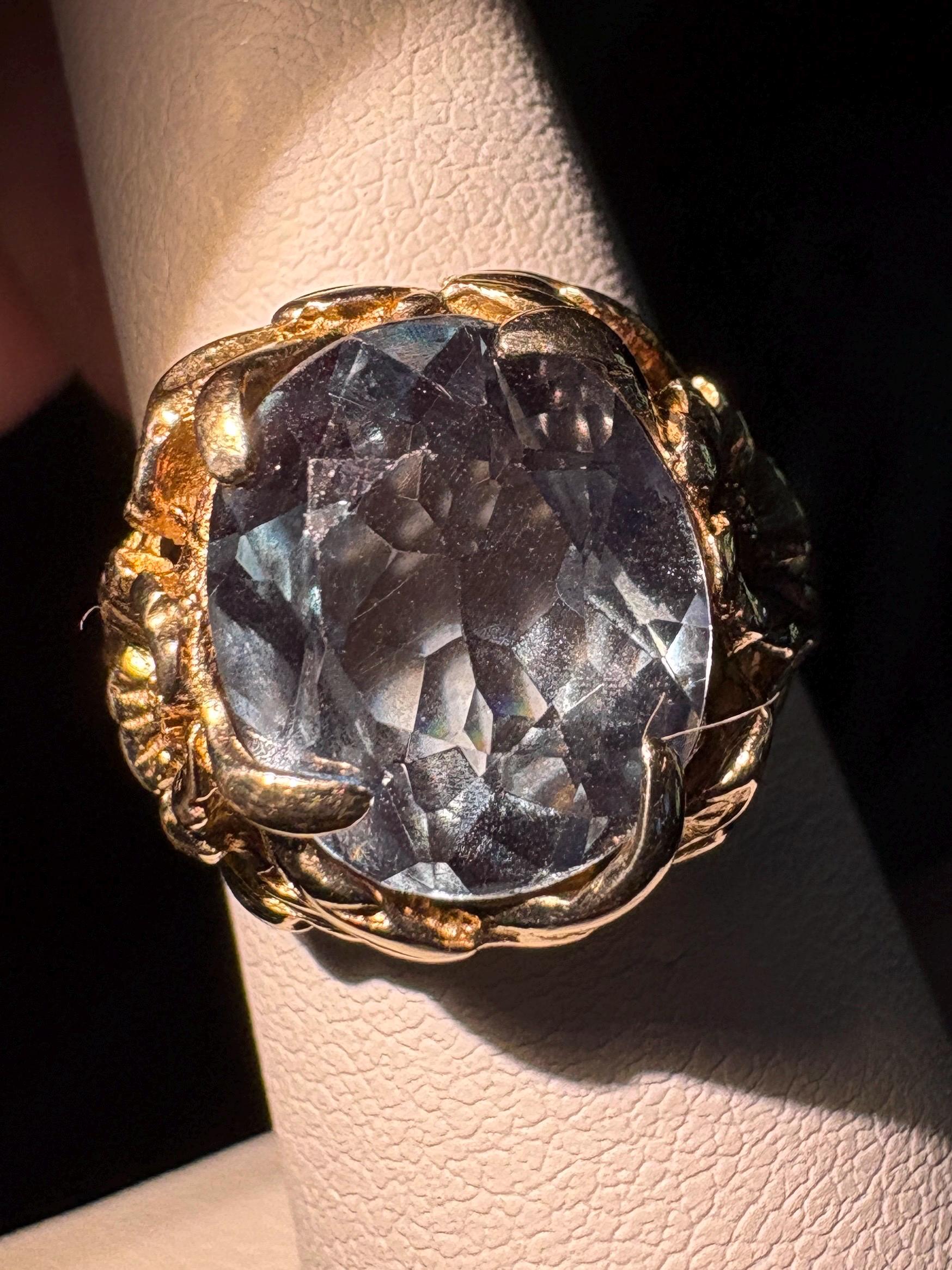 Large oval color shift synthetic spinel ring with floral accents in 10k gold.