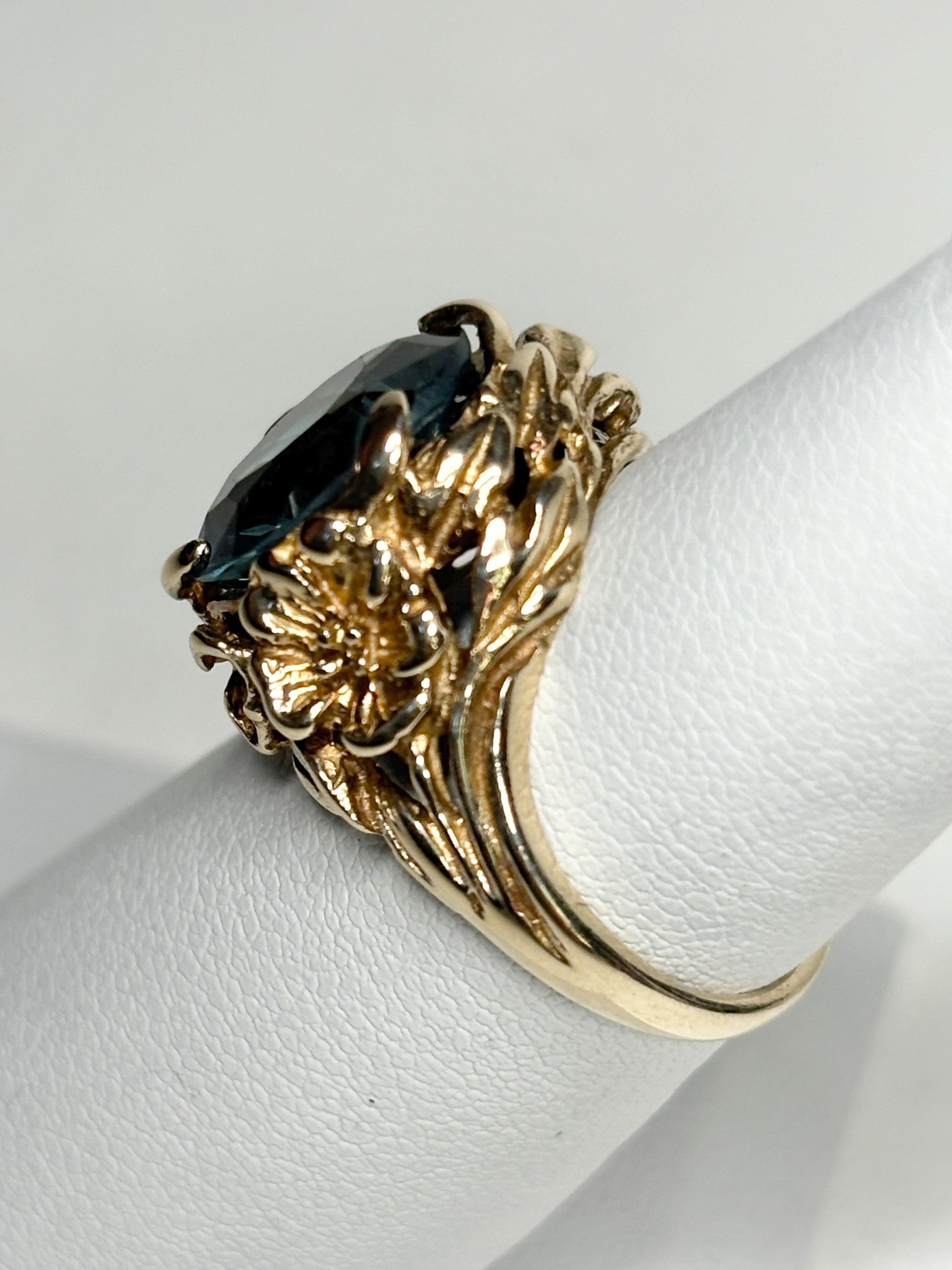 A large 10k gold ring with a blue synthetic spinel and floral details.