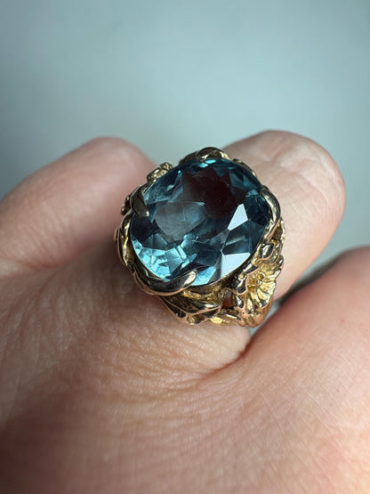 Large mid-century 10k gold ring with a blueish synthetic spinel and floral details.