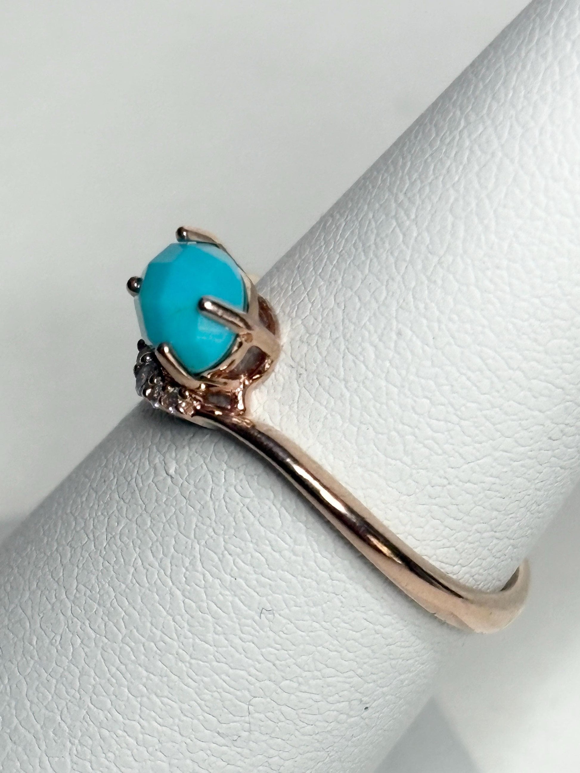 A rose gold ring with a checkerboard faceted turquoise stone and small diamonds.