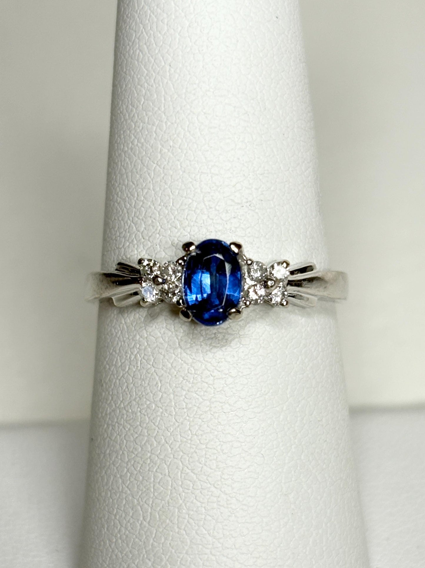A 10k white gold ring featuring an oval blue kyanite center stone and eight small diamonds.
