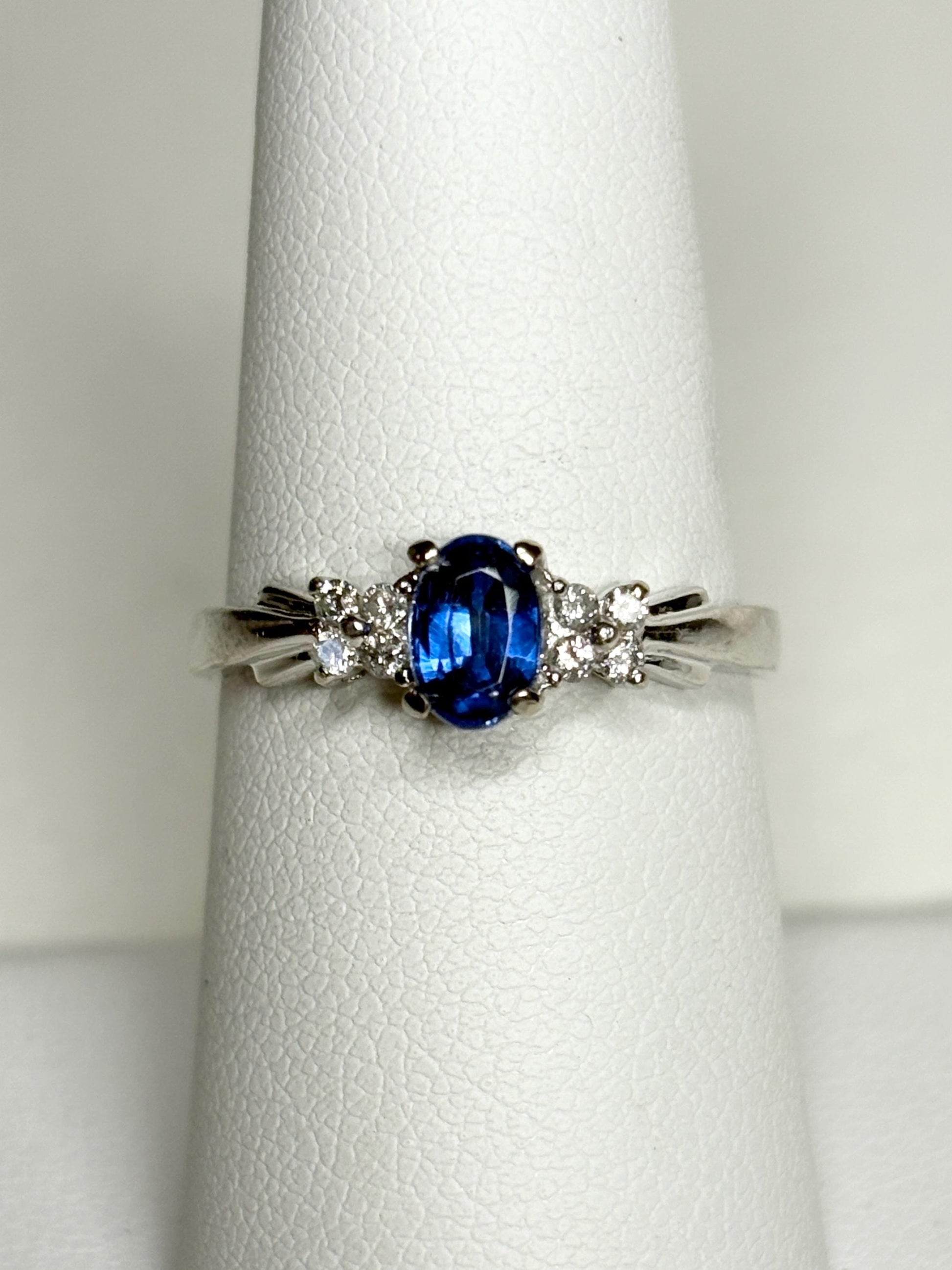 A 10k white gold ring featuring an oval blue kyanite center stone and eight small diamonds.