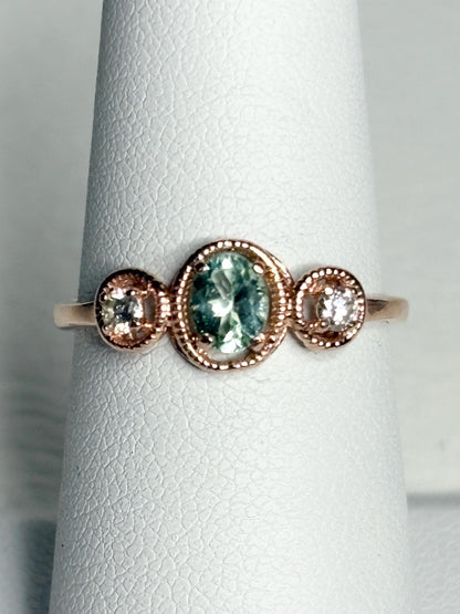 14k rose gold ring with a central oval Paraiba colored tourmaline and two side diamonds.