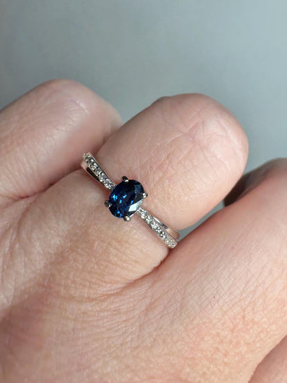 A blue sapphire and diamond crossover band ring in 10k gold.