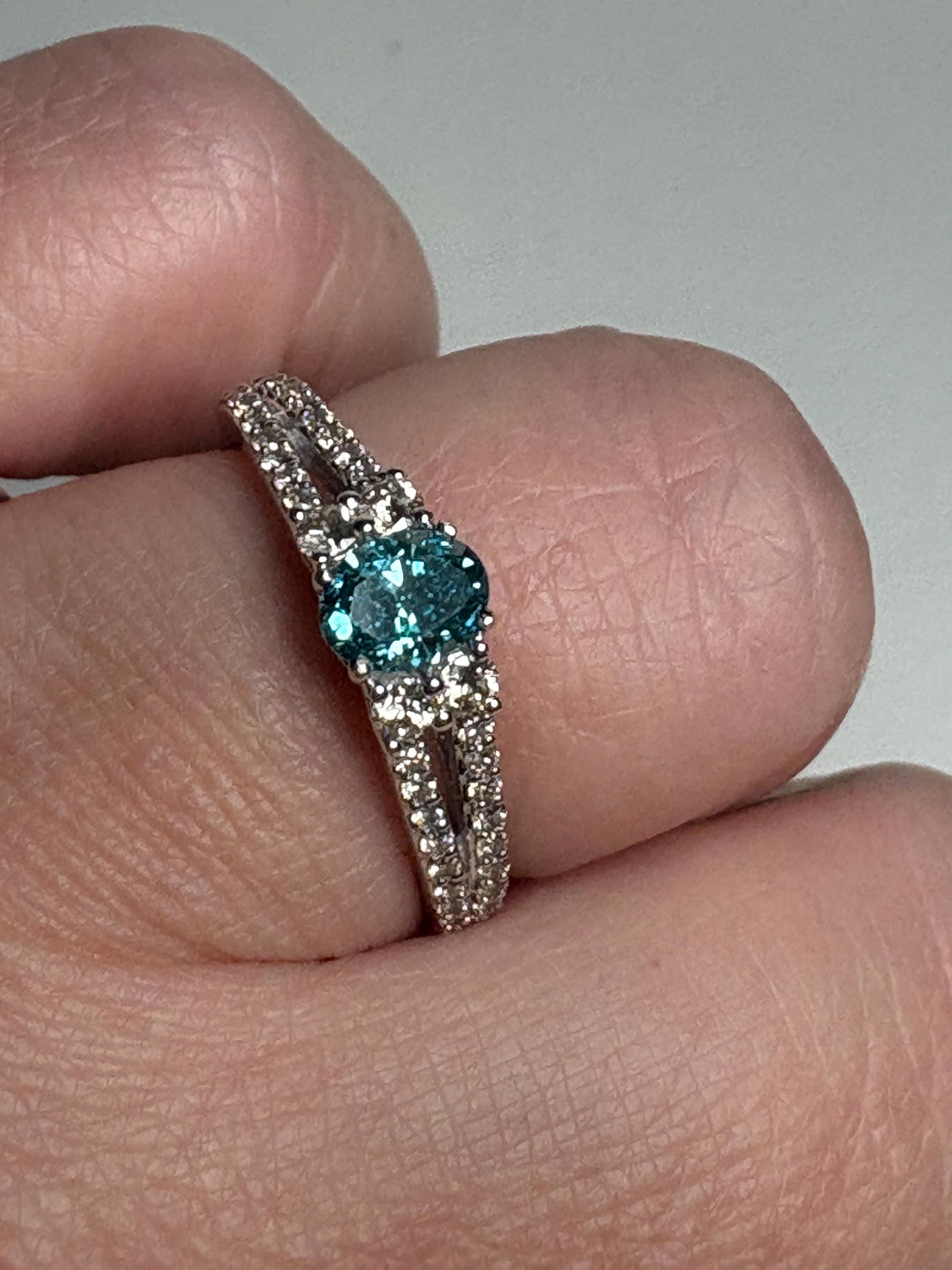 A white gold ring with a blue diamond and champagne diamonds.