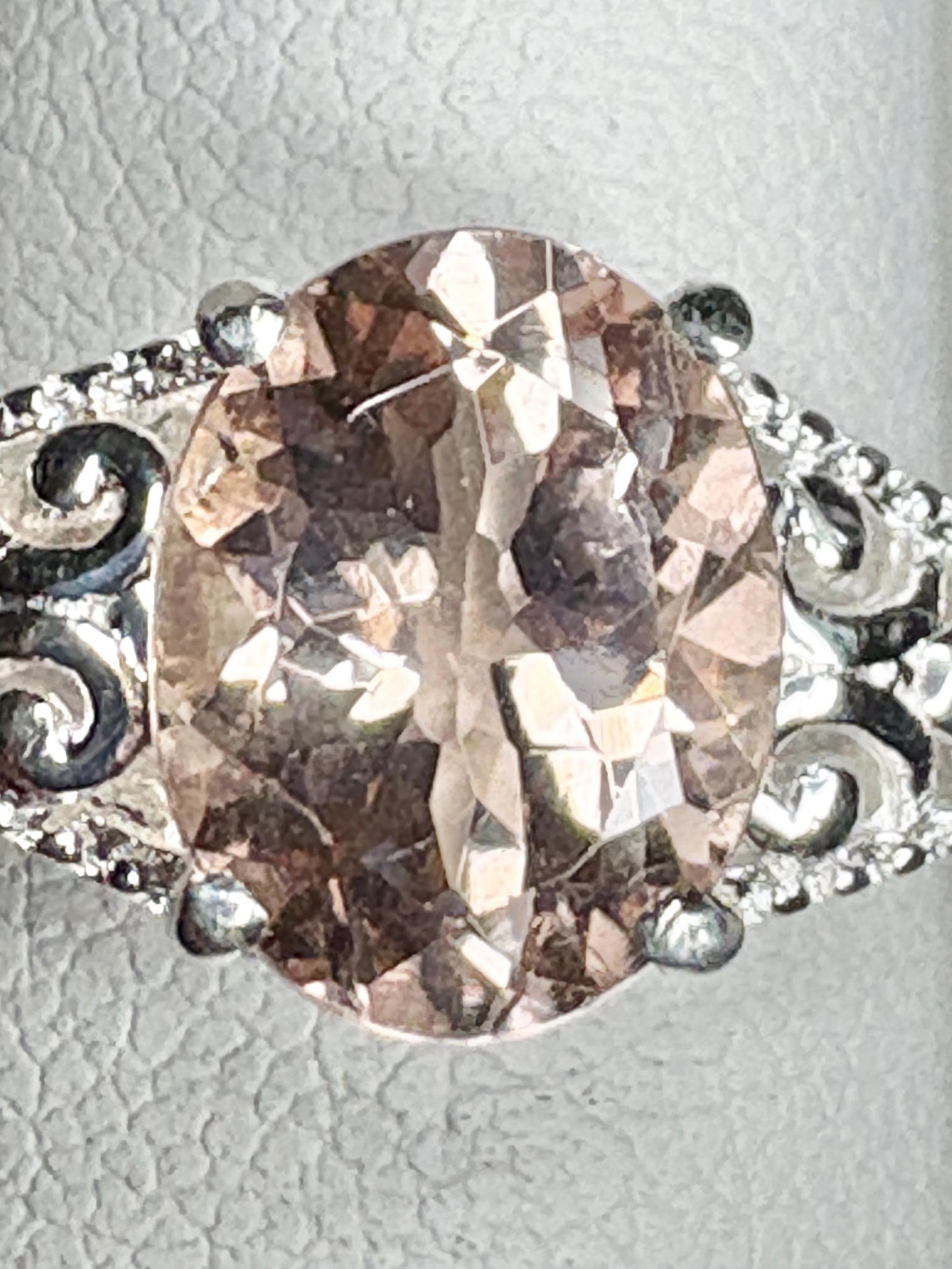Oval morganite gemstone in a sterling silver ring with ornate details.
