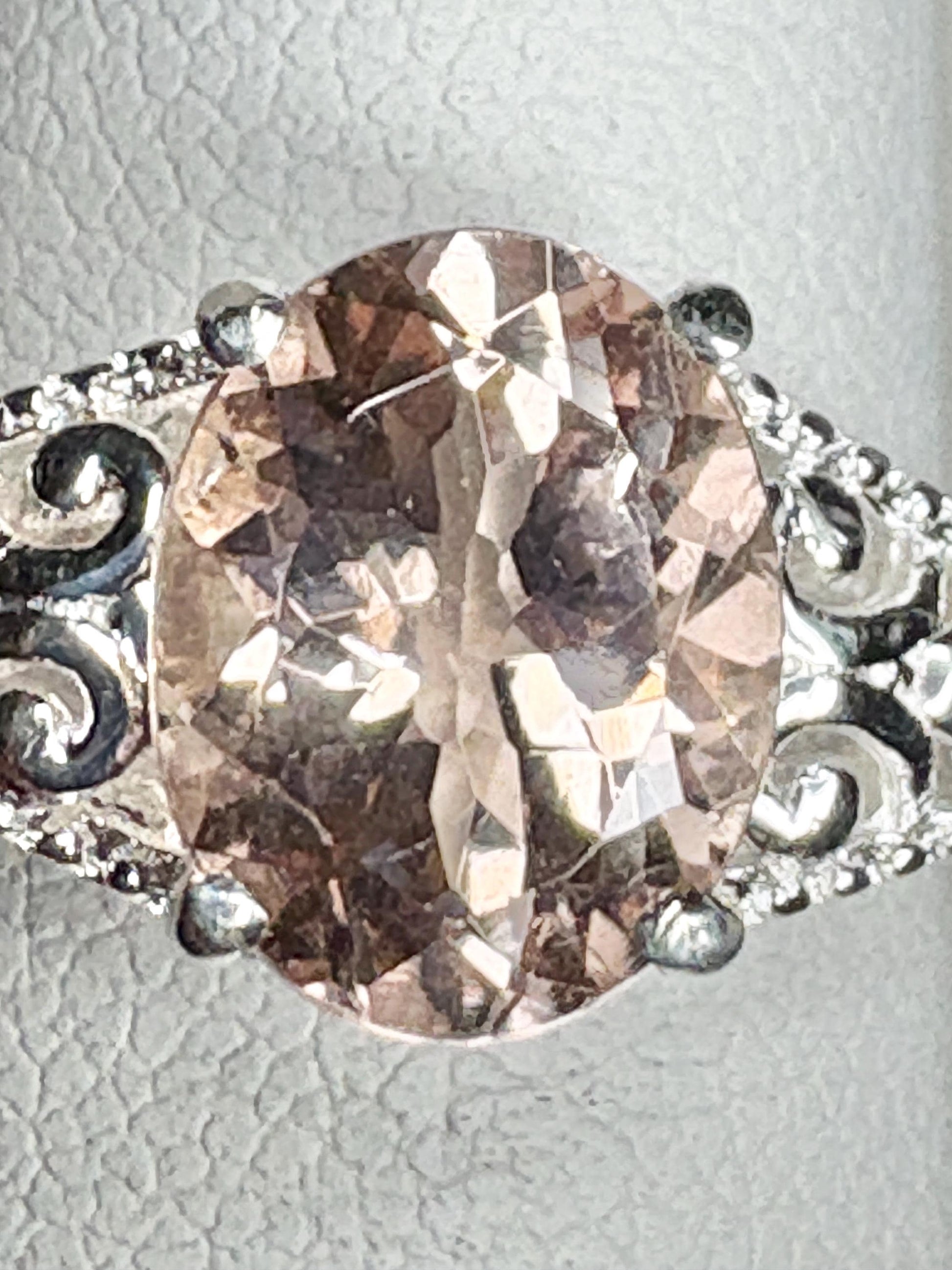 Oval morganite gemstone in a sterling silver ring with ornate details.