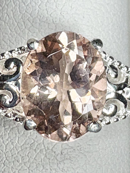 Oval morganite gemstone in a sterling silver ring with ornate details.