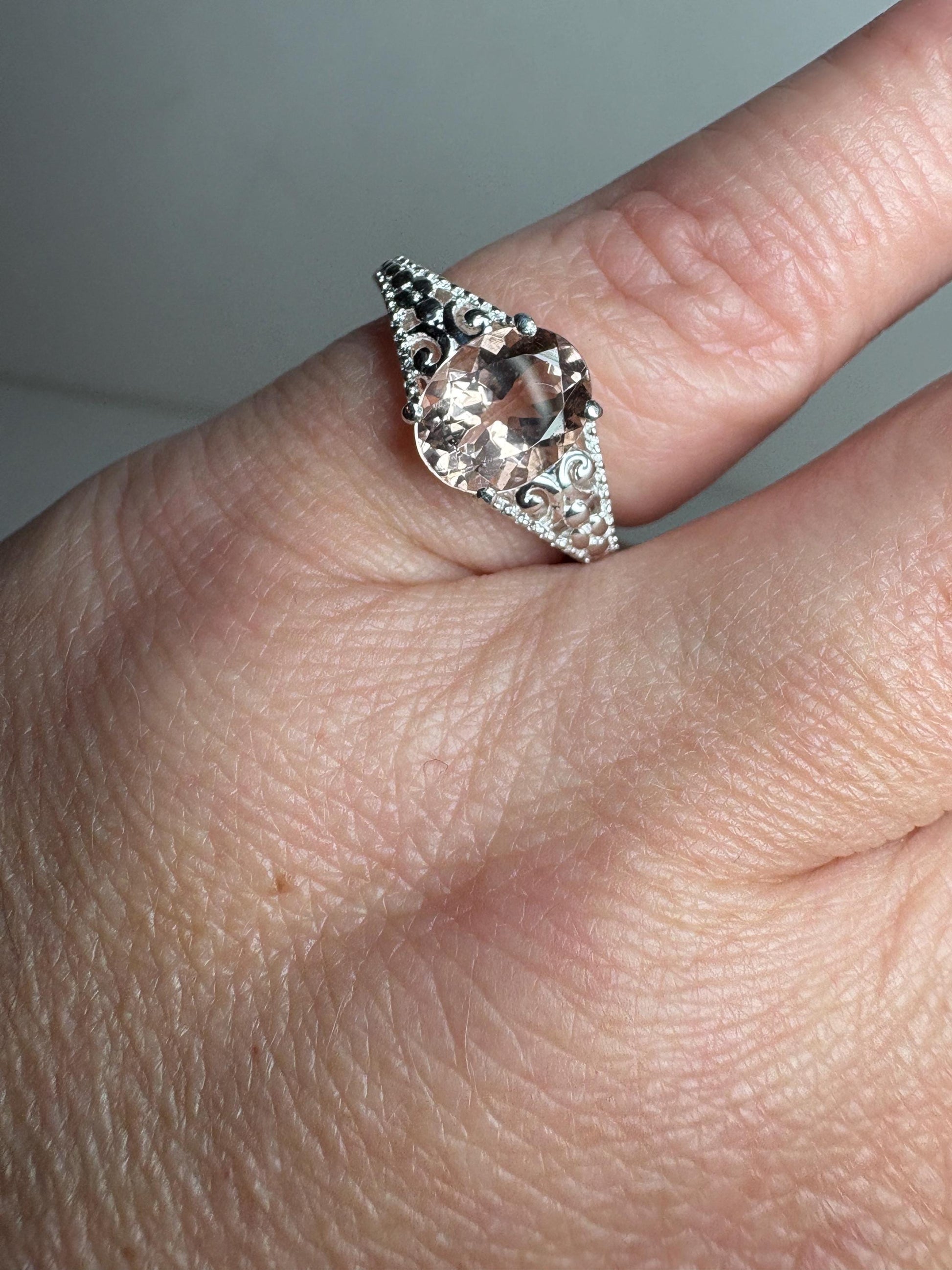 Sterling silver ring with a large oval morganite and ornate detailing.